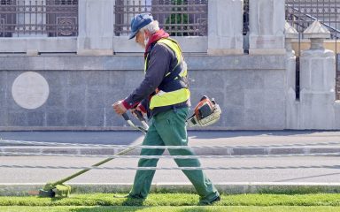 Motoros fűkaszával vágja a füvet egy férfi