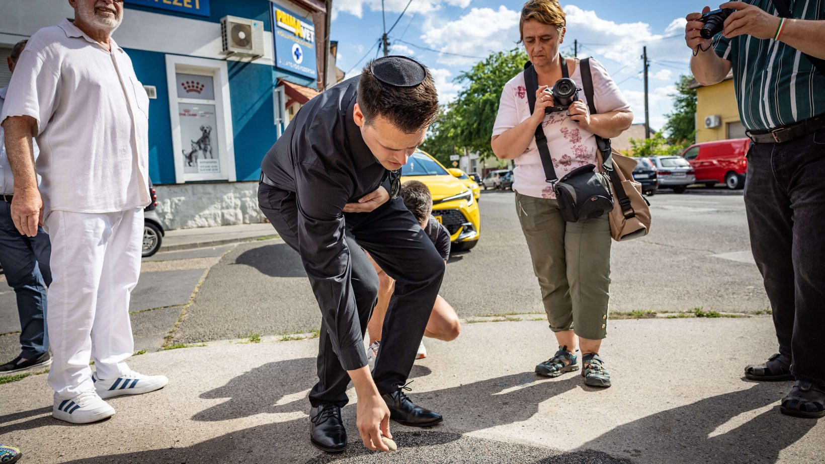 Csernák János mécsest gyújt a botlatókőnél